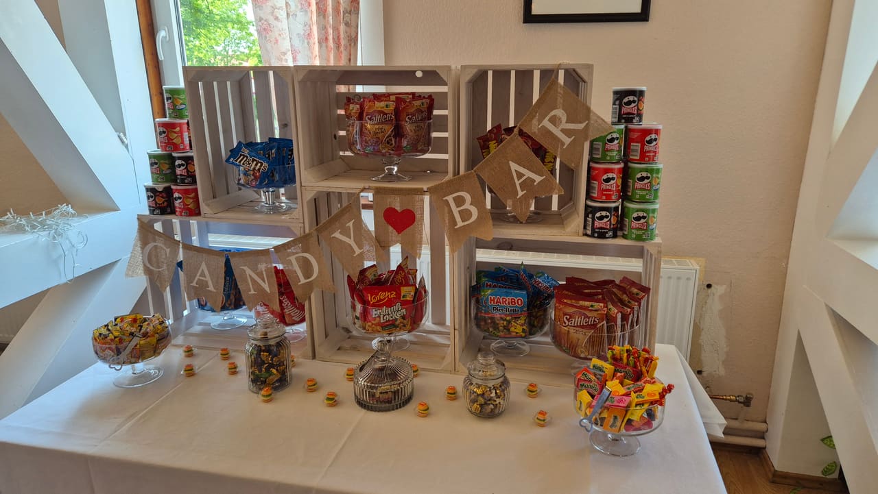 Candy-Bar aus weißen Holzkisten mit Süßigkeiten, Chips und Wimpelkette