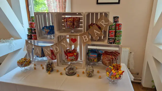 Candy-Bar aus weißen Holzkisten mit Süßigkeiten, Chips und Wimpelkette