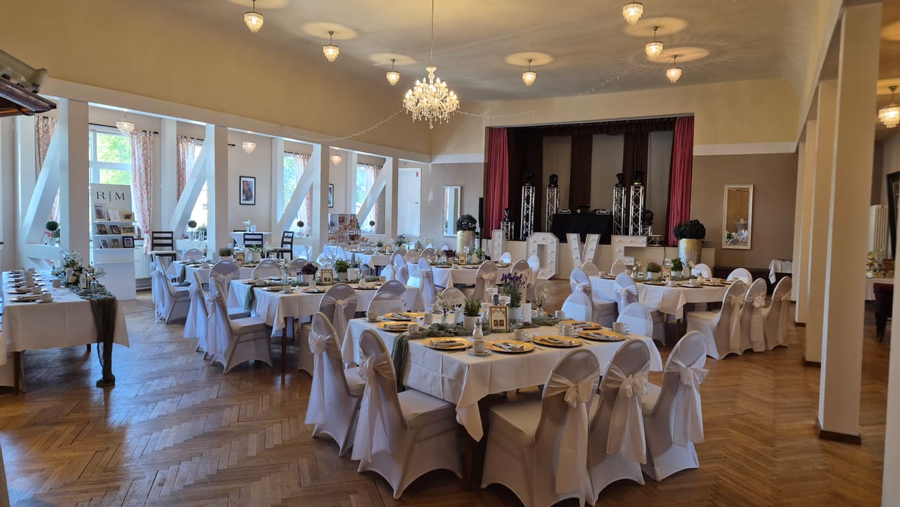Festlich gedeckter Festsaal im Schützenhaus Heldburg mit Kronleuchtern und langen Tafeln, hergerichtet für eine Hochzeit
