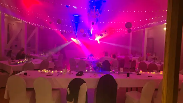 Feiernde Gäste unter farbiger Lichtshow und Nebel